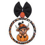 Cute Highland cow wearing a jack-o-lantern beanie while sitting inside a pumpkin.