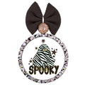 Zebra-striped ghost with star earrings surrounded by black and gold stars above the word Spooky.