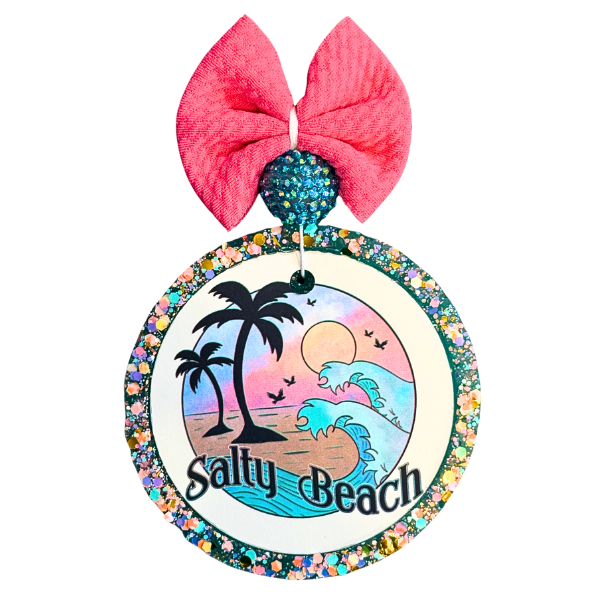 Decorative ornament with 'Salty Beach' design and pink bow on a white background